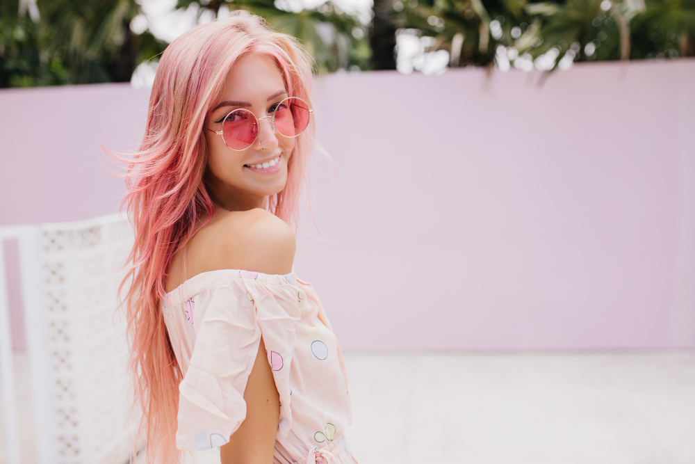 Mujer con cabello rosa pastel largo y ondulado como tendencia de coloración en 2026