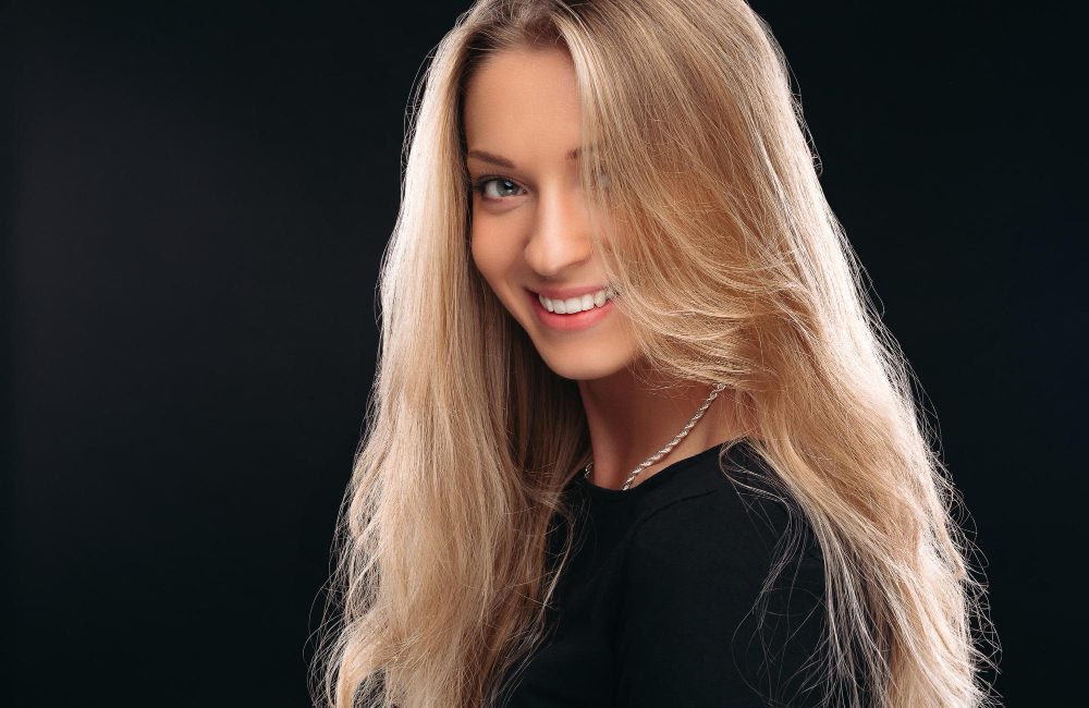 Mujer con cabello rubio largo con efecto balayage natural y brillo